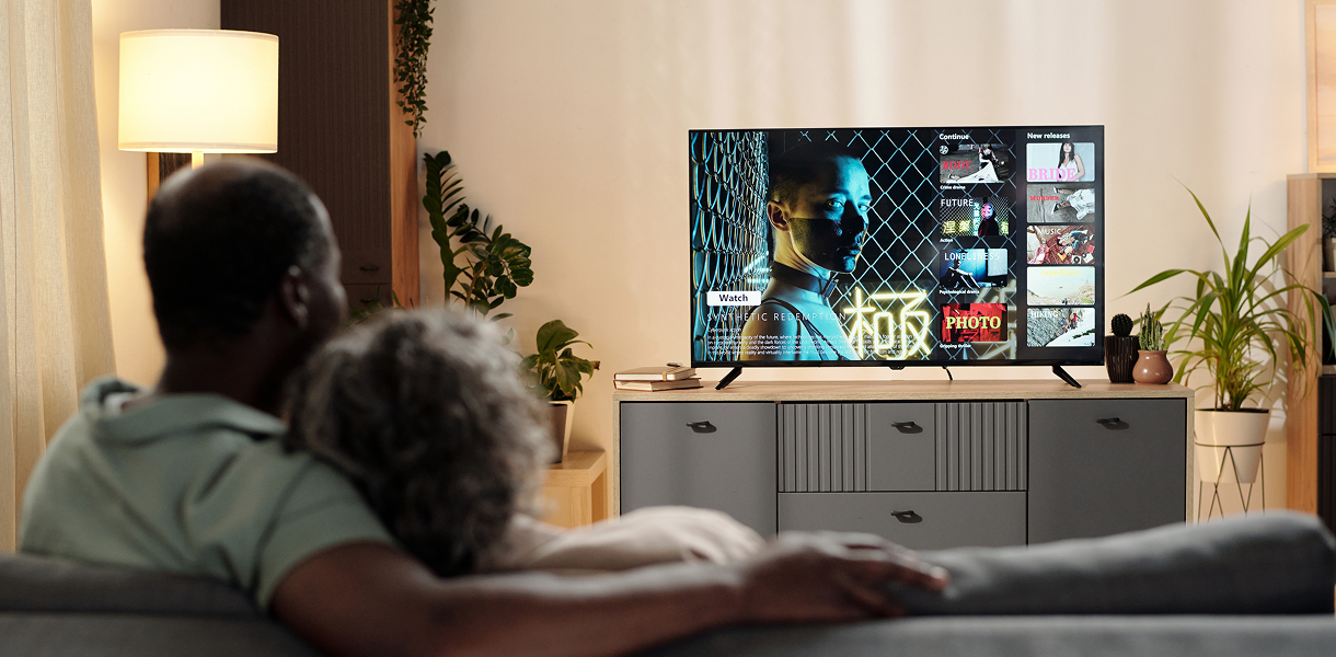 Relaxing on couch with television screen visible.