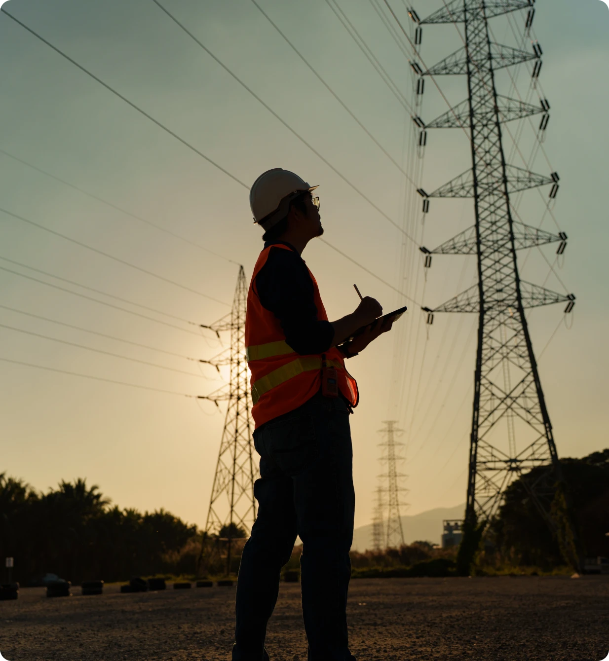 Engineer inspecting power lines at sunset.