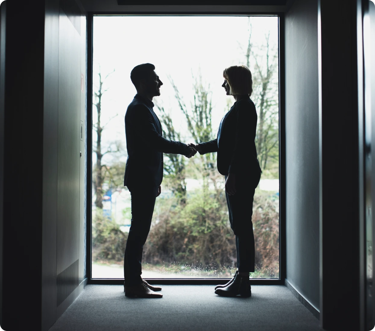 Silhouetted handshake in office hallway